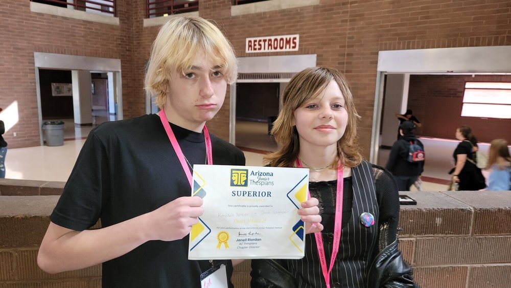 two students holding drama award