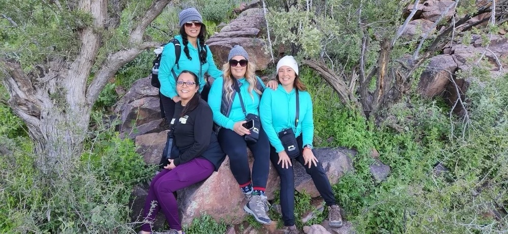 four women sitting on a rock